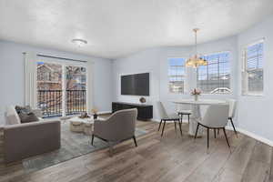 Living area featuring a textured ceiling, hardwood / wood-style floors, and a chandelier