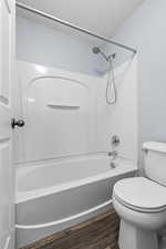 Full bath featuring washtub / shower combination, a textured ceiling, and dark wood finished floors