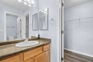 Bathroom featuring a textured ceiling, vanity, a walk in closet, and dark wood-type flooring