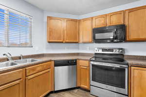 Kitchen featuring appliances with stainless steel finishes, dark countertops, a textured ceiling, and light wood-style floors