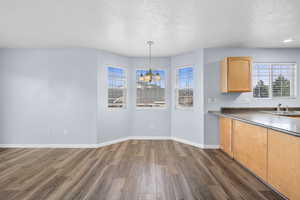 Unfurnished dining area with a textured ceiling, dark wood finished floors, and a chandelier