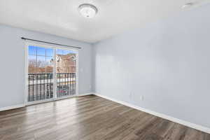 Spare room with a textured ceiling, wood finished floors, and a smoke detector