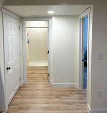Hall with light wood-style flooring and recessed lighting