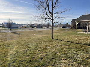 View of green lawn with a residential view and a patio