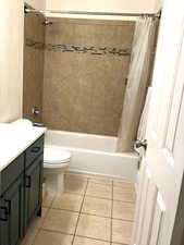 Bathroom with vanity, shower / bath combo with shower curtain, and light tile patterned flooring