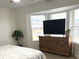Bedroom with ornamental molding, carpet flooring, and a ceiling fan