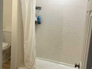 Full bathroom featuring a shower stall and light wood-style flooring