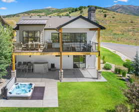 View of patio / terrace with a hot tub, a mountain & lake view.