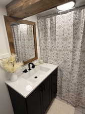 Full bathroom with vanity, a wainscoted wall, and a shower with curtain