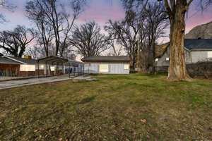 Yard at dusk featuring a carport, driveway, and a patio