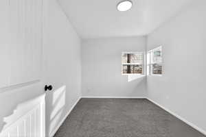 Spare room with dark carpet and baseboards