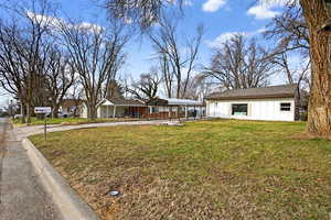 View of front of house featuring a front lawn, a carport, board and batten siding, and a residential view
