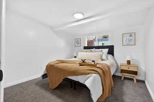 Bedroom with carpet floors and beamed ceiling