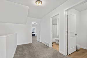 Hallway with light carpet and baseboards