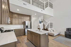 Kitchen featuring light wood-style floors, a center island with sink, stainless steel appliances, recessed lighting, and light stone counters