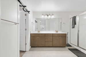 Full bathroom featuring double vanity, a shower stall, and light tile patterned floors