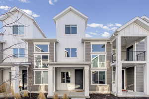 View of front facade with board and batten siding, a balcony, and covered porch