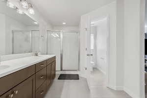 Full bath featuring double vanity, a stall shower, light tile patterned floors, and recessed lighting