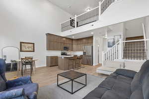 Living area featuring light wood finished floors, a towering ceiling, and stairs