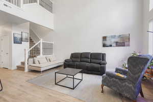 Living room featuring a towering ceiling, light wood finished floors, and stairs