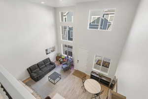 Living area featuring wood finished floors, recessed lighting, and a high ceiling