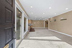 Entryway featuring recessed lighting, light colored carpet, and ornamental molding