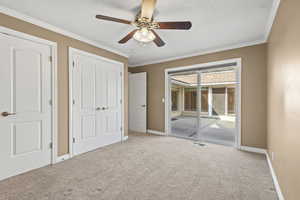 Unfurnished bedroom with access to exterior, carpet flooring, ornamental molding, a closet, and a ceiling fan