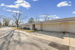 View of front of house with driveway, brick siding, a garage, and a residential view
