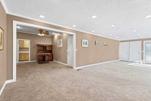 Unfurnished living room with light colored carpet, a textured ceiling, crown molding, recessed lighting, and ceiling fan