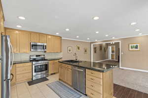 Kitchen featuring appliances with stainless steel finishes, tasteful backsplash, recessed lighting, light brown cabinetry, and a kitchen island with sink