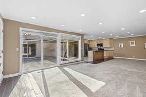 Kitchen with open floor plan, crown molding, dark countertops, appliances with stainless steel finishes, and a kitchen island