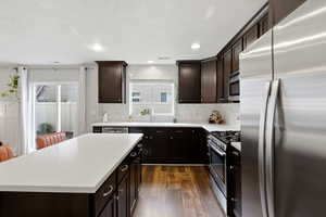 Kitchen with stainless steel appliances, dark brown cabinetry, healthy amount of natural light, a textured ceiling, and recessed lighting