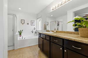 Full bath featuring vanity, a garden tub, a stall shower, and light tile patterned floors