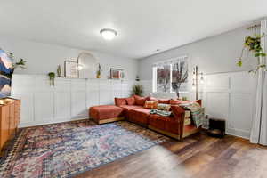 Bedroom with a decorative wall, wood finished floors, and wainscoting