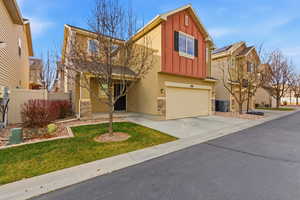 Traditional-style home with board and batten siding, stone siding, an attached garage, concrete driveway, and stucco siding