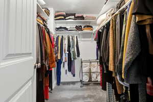 Walk in closet featuring light colored carpet