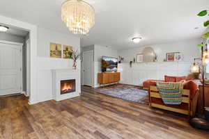 Living room featuring a lit fireplace, a chandelier, and wood finished floors