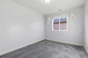 Spare room featuring carpet flooring and baseboards