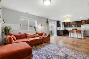 Living room with a decorative wall, a chandelier, wainscoting, light wood finished floors, and recessed lighting