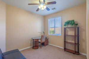 Home office with light colored carpet and a ceiling fan