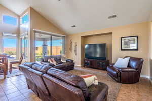 Living room featuring healthy amount of natural light, light tile patterned floors, and high vaulted ceiling