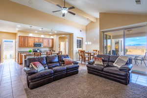 Living area with light tile patterned floors, arched walkways, a mountain view, beamed ceiling, and a ceiling fan