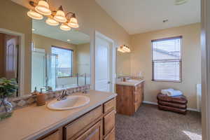 Bathroom with a garden tub, a stall shower, two vanities, and dark colored carpet