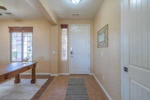 Foyer entrance with light tile patterned floors and baseboards