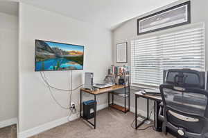 Office with light carpet and vaulted ceiling