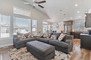 Living area featuring light wood-style flooring, ceiling fan, a chandelier, recessed lighting, and high vaulted ceiling