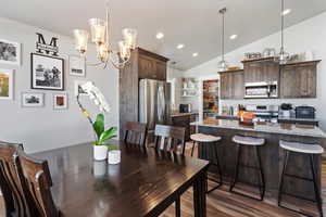Dining area featuring vaulted ceiling, light wood finished floors, a chandelier, and recessed lighting