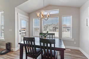 Dining room featuring light wood-style flooring, a chandelier, and lofted ceiling