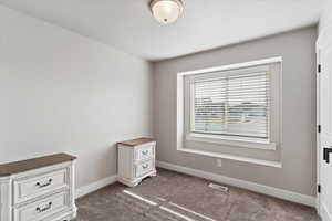 Unfurnished bedroom featuring dark colored carpet and baseboards