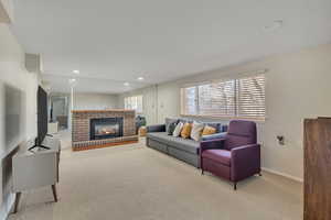 Carpeted living area featuring a brick fireplace and recessed lighting